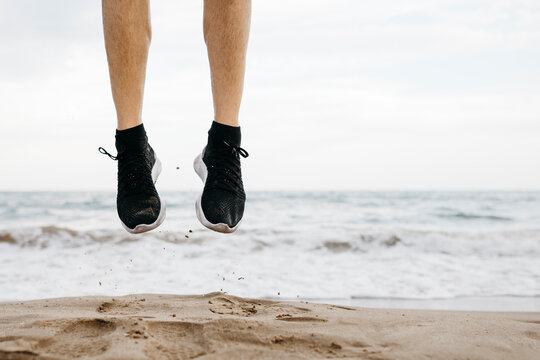 Legs of man jumping on the beach while training