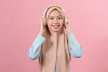 A young smiling muslim girl listens to her favorite music in white headphones, look at the camera, enjoyment, music lover