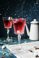 Glass of hot red tea with splash on table
