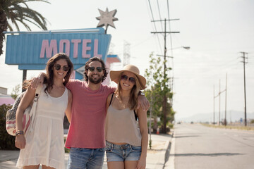 Smiling male and female friends in sunglasses standing on sidewalk during sunny day