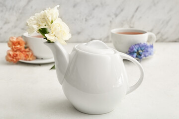 Fototapeta na wymiar Tea pot with flowers on table