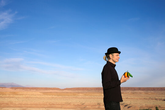 Morocco, Ounila Valley, man wearing a bowler hat holding an orange