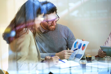 Three business people having a meeting in modern office sharing graphs
