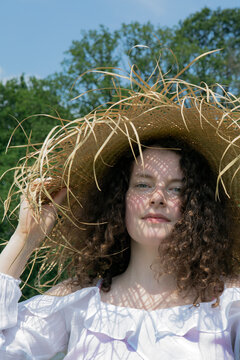 Portrait of young woman wearing frayed straw hat in nature