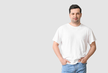 Handsome young man in stylish t-shirt on light background