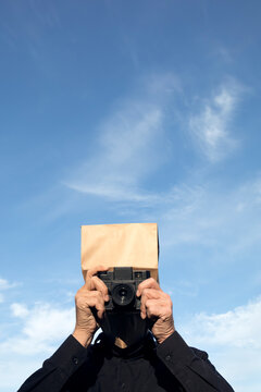 Man with paper bag above his head taking a picture