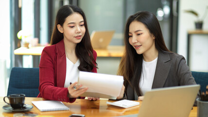 Obraz premium Two young smart business women working together on financial documents