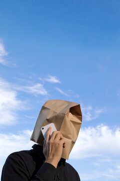 Man with paper bag above his head talking on cell phone