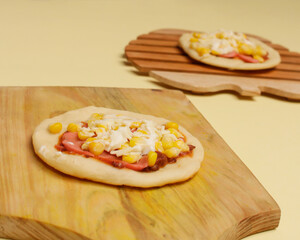 Mini pizza with corn, sausage and cheese topping for your lunch menu. pizza is a savory dish from Italy a kind of round and flat dough, baked in the oven. Pizza mockups. Focus blur. Focus on some ange