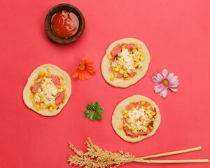 Fototapeta na wymiar Mini pizza with corn, sausage and cheese topping for your lunch menu. pizza is a savory dish from Italy a kind of round and flat dough, baked in the oven. Pizza mockups. Focus blur. Focus on some ange