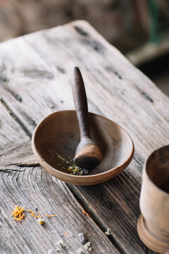 Flowers and herbs in earthenware bowl with pestle on wooden table