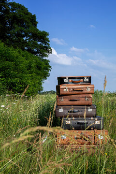 Stack of old leather suitcases on a meadow