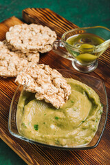 Bowl with tasty baba ghanoush and rice crackers on color background, closeup
