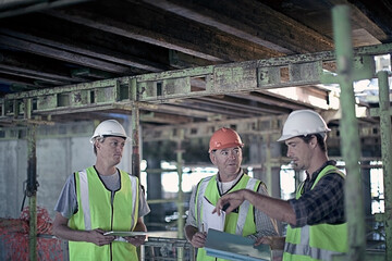 Male construction worker discussing with coworkers at construction industry