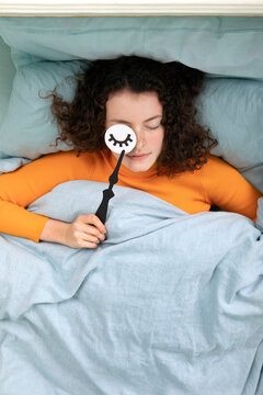 Portrait of sleeping young woman lying in bed with paper mask