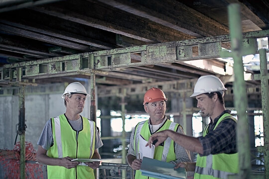 Male construction worker discussing with coworkers at construction industry