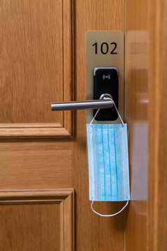 Protective face mask hanging on door lock