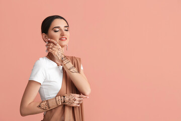 Beautiful Indian woman with henna tattoo on color background