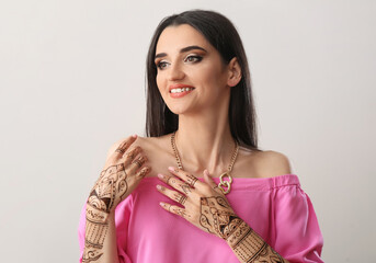 Beautiful Indian woman with henna tattoo on light background