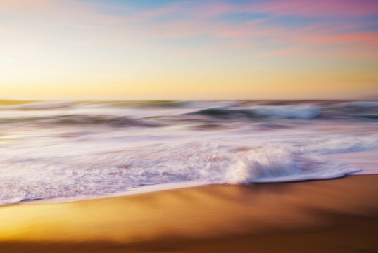 Spain, Province of A Coruna, Ferrol, Long exposure of ocean waves brushing sandy coastal beach at dusk