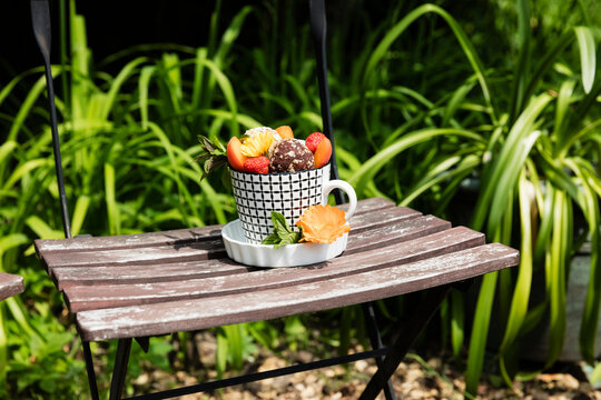 Dessert with energy balls (raw confectionery) and fresh fruits and flowers on garden chair