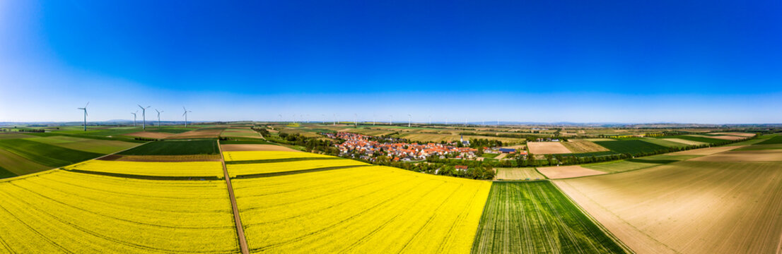 Germany, Rhineland-Palatinate, Gabsheim, Helicopter view of countryside fields and village in summer with wind farm in background