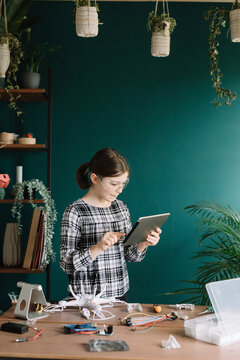 Girl using digital tablet while making drone on table at home