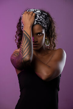 Portrait of serious young woman with tattooed arm against purple background
