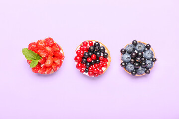 Tasty berry tartlets on purple background