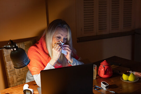 Senior Woman Crying While Looking At Video Call On Laptop While Sitting At Home