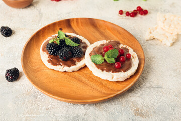 Plate with puffed rice crackers and berries on light background