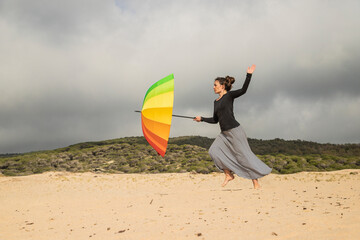Woman holding colorful umbrella on a dune