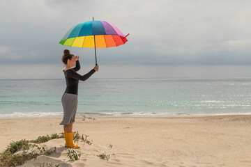 Woman with colorful umbrella sitting on the beach
