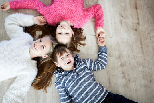 Happy siblings lying on the floor, laughing