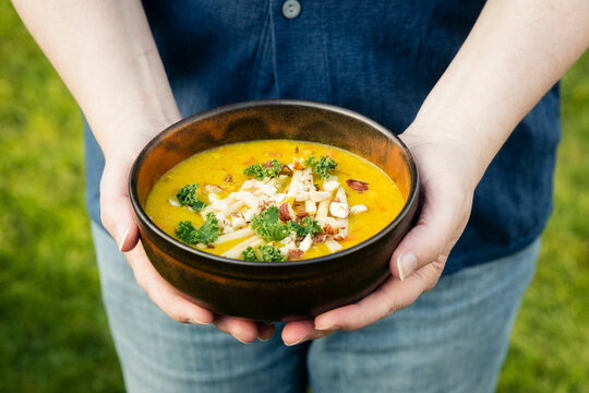 Mans hands holding bowl with dal of lentils, potatoes and vegetables