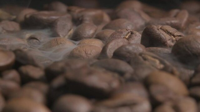 Close up slow motion shot of smoke released during the roasting of organic coffee beans. The exothermic reaction transforms the raw green beans which gives the coffee its aromatic smell and taste.