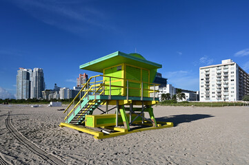 Colorful lifeguard station on Miami Beach, Florida under late summer cloudscape in early morning light with residential towers in background.