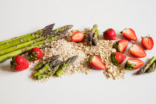 Studio shot of oats, asparagus stalks and halved strawberries