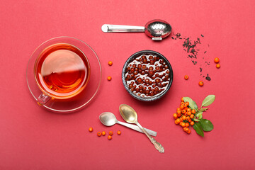 Composition with bowl of tasty rowan jam and cup of tea on color background