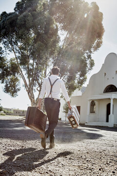 Man in old-fashioned clothes with suitcases in the countryside