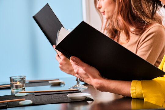 Young women reading menu while sitting at table in restaurant
