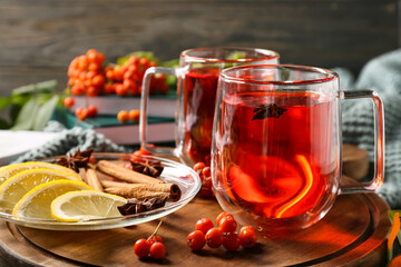 Board with glass cups of tasty rowan tea, lemon and spices, closeup