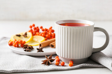 Obraz na płótnie Canvas Cup of delicious rowan tea and spices on table