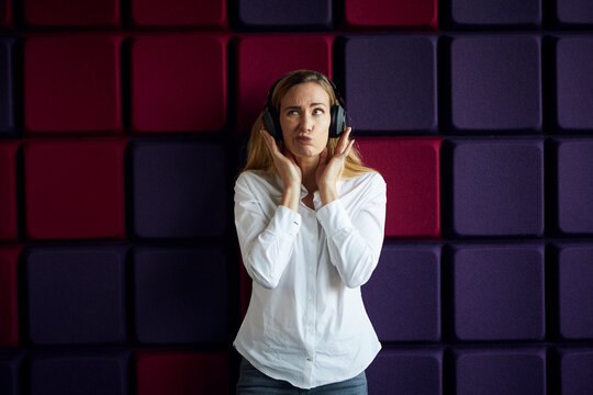 Portrait of woman at a purple wall listening to music with headphones