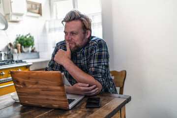 Man using laptop on kitchen table