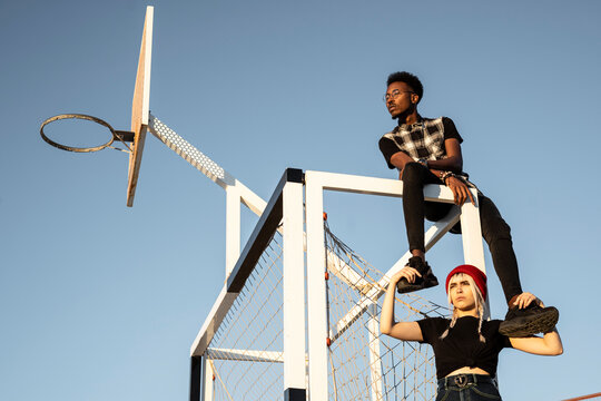 Young couple sitting at soccer goal against sky