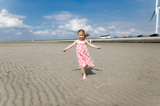 Happy little girl running on the beach, Bergen op Zoom, Netherlands