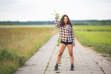 Happy woman with drumsticks standing on road in field