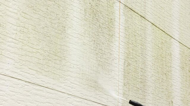 Man cleaning walls with high pressure power washer. Washing cladding walls house. High quality 4k footage