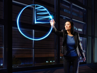 Asian businesswoman painting cake chart with light